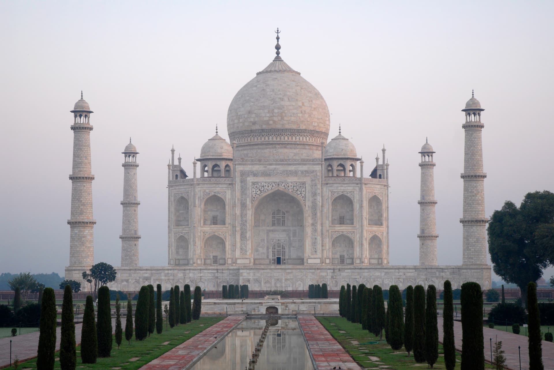 Taj Mahal southern facade with the central dome, four minarets, and reflecting pool — ivory-white marble mausoleum in Agra at midday.