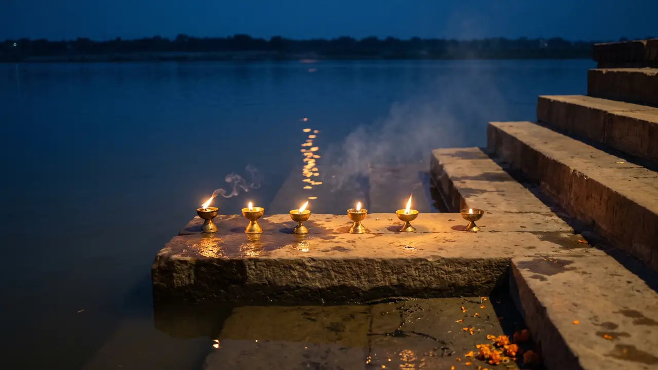 Worn stone ghat steps at blue hour with six brass oil lamps spaced along one tread, their flames mirrored in the wet stone above dark, still water.